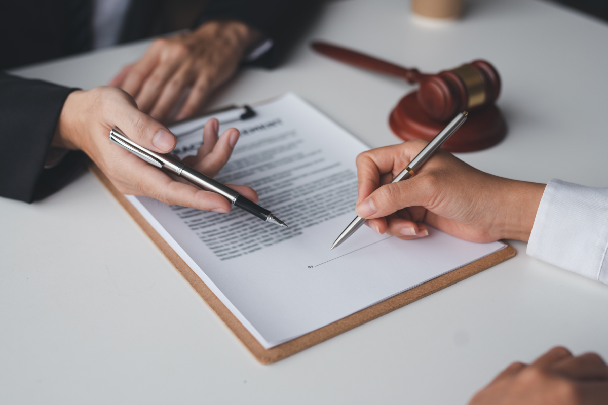 Signing a document with gavel nearby.