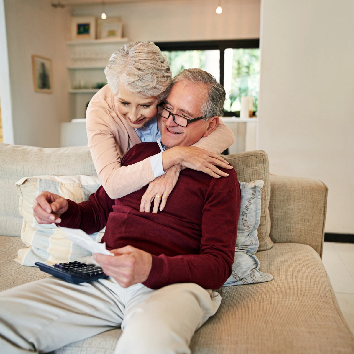 Elderly couple hugging on a couch.