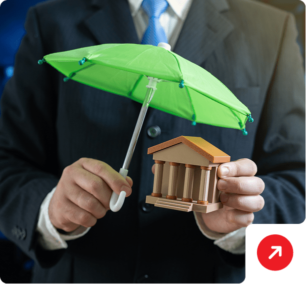 Person holding umbrella and small house model.
